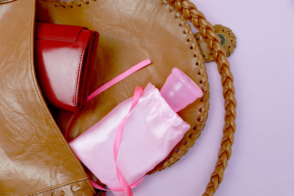 Coupe menstruelle dans un sac à main, style de vie. Le concept de la santé des femmes, de l'éco et de la vie sans déchets
 - Photo, image