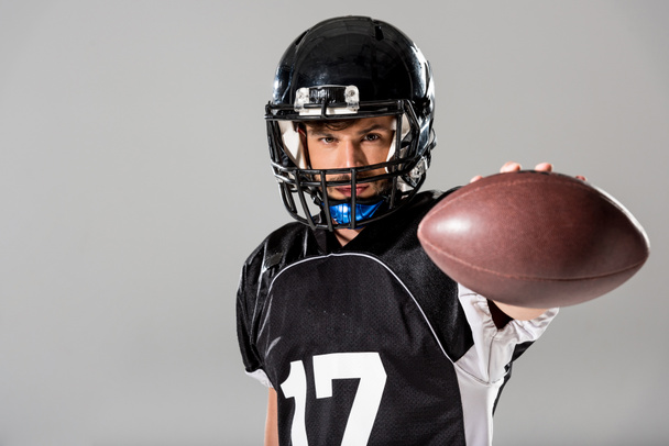 Американский футболист с мячом, изолированным от серого
 - Фото, изображение