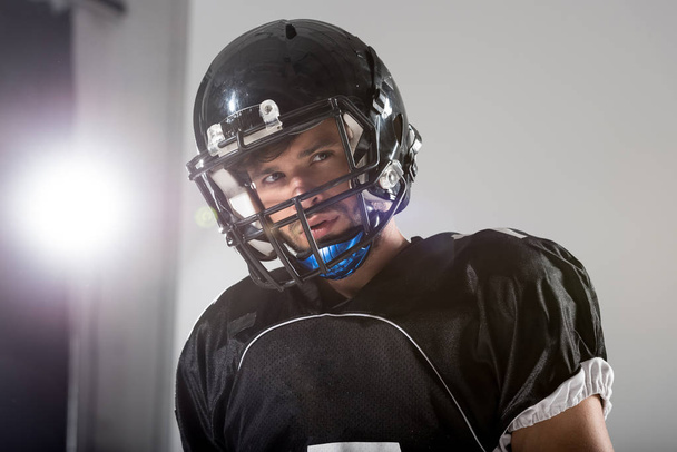 Американский футболист в шлеме на сером с подсветкой
 - Фото, изображение