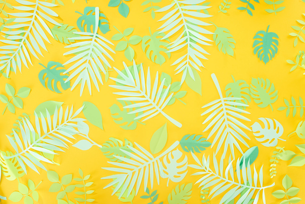 top view of paper cut green tropical leaves on yellow bright background with copy space - Foto, Imagem