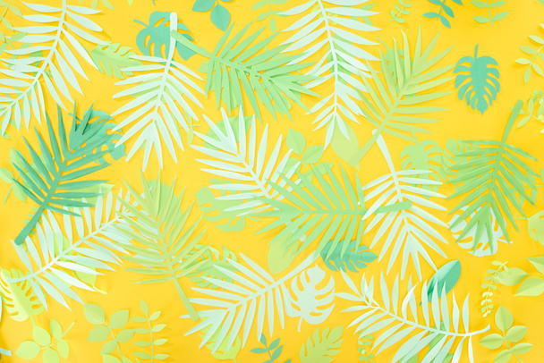 vista superior do papel cortar folhas tropicais verdes no fundo brilhante amarelo com espaço de cópia
 - Foto, Imagem