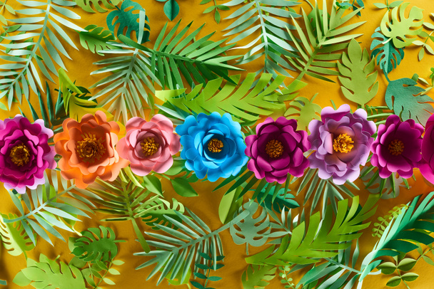 flat lay with paper cut flowers on tropical leaves on yellow bright background - Valokuva, kuva