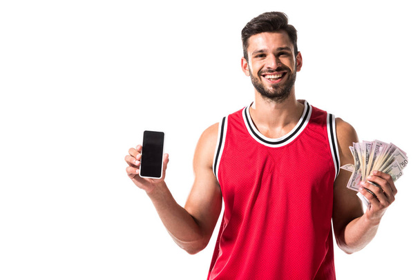 gelukkige basketbalspeler houdt geld en smartphone geïsoleerd op wit  - Foto, afbeelding