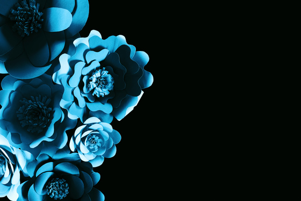 bovenaanzicht van papier gesneden blauwe bloemen geïsoleerd op zwart met Kopieer ruimte - Foto, afbeelding