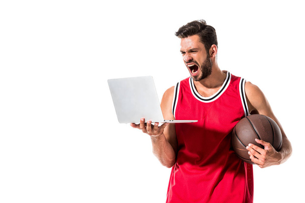 gritando jogador de basquete com bola usando laptop isolado em branco
  - Foto, Imagem
