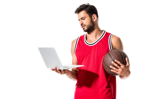 atletico giocatore di basket in uniforme con palla utilizzando il computer portatile isolato su bianco
  - Foto, immagini