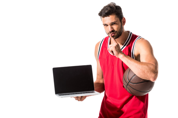 atletische basketbalspeler met bal en laptop doen stilte gebaar geïsoleerd op wit  - Foto, afbeelding