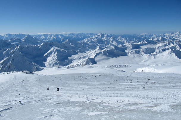 Hermosas vistas de la cresta y los picos de montaña. Snowboarders ir por la pendiente de la carretera
. - Foto, Imagen