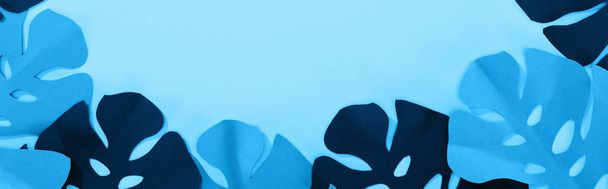 top view of paper cut tropical leaves on blue minimalistic background with copy space, panoramic shot - Photo, image