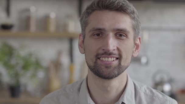 Portrait of bearded guy confidently looking at camera enjoying executive lifestyle on the background of a modern kitchen. Real people series - Imágenes, Vídeo