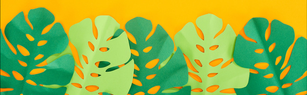 top view of paper cut green tropical leaves on yellow bright background, panoramic shot - Photo, Image