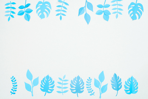 Kopyalama alanı ile beyaz üzerinde izole mavi kağıt kesmek tropikal yaprakları üst görünümü - Fotoğraf, Görsel