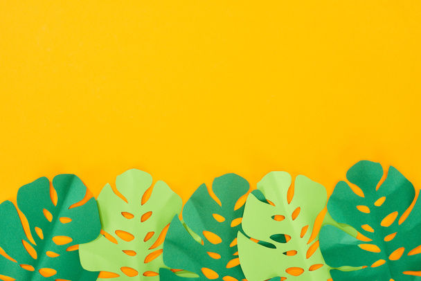 top view of paper cut green tropical leaves on yellow bright background with copy space - Zdjęcie, obraz