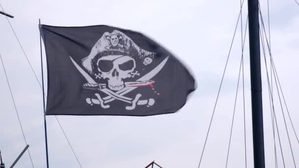 Piracka Flaga Jolly Roger wiszące na maszcie statku na niebieskim tle nieba w wietrzny dzień. - Materiał filmowy, wideo