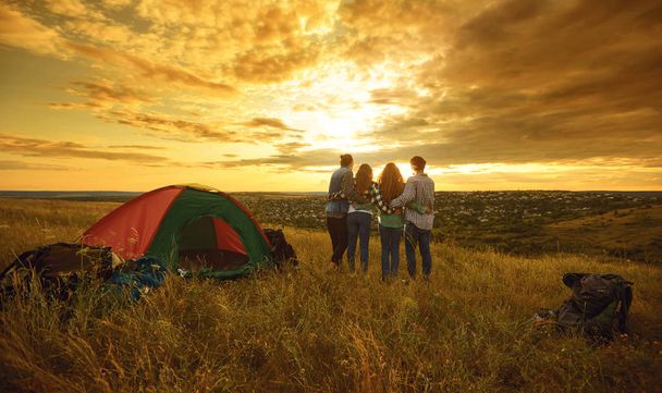 Camping acampamento de tenda pessoas turistas sentados no pôr do sol na natureza
. - Foto, Imagem