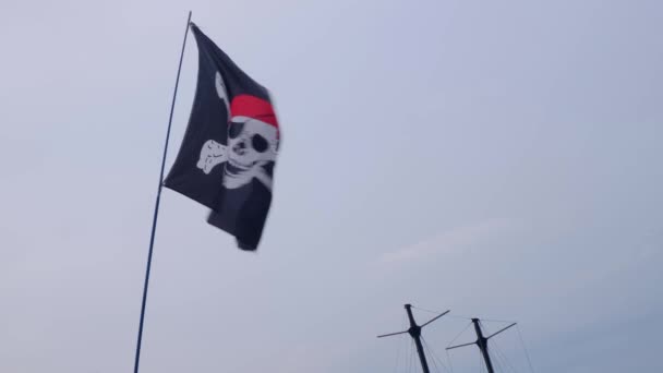 Piratenflagge lustiger Roger hängt an einem Schiffsmast auf blauem Himmel Hintergrund bei windigem Tag. - Filmmaterial, Video