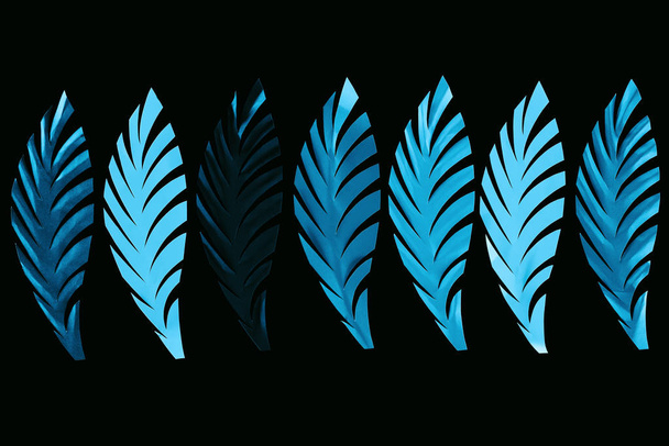 top view of paper cut blue leaves in row isolated on black, background pattern - Photo, Image