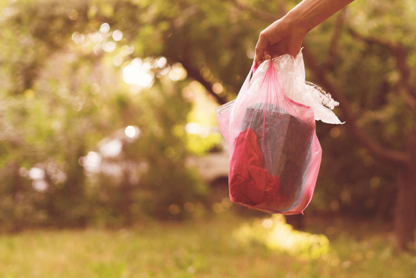persona recoge el paquete y saca la basura, cuidar de la naturaleza y el parque
 - Foto, Imagen