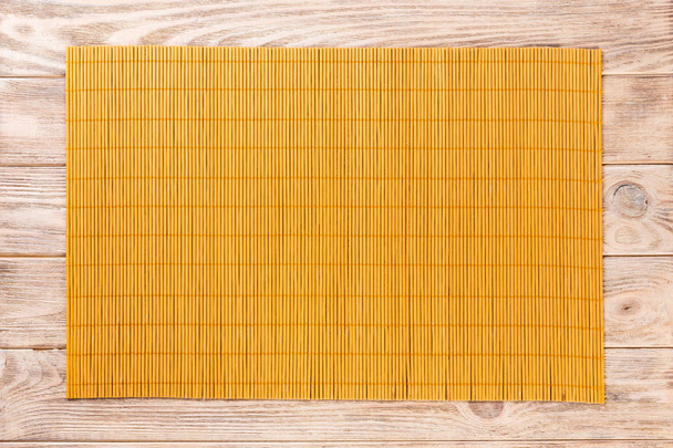 Üres ázsiai élelmiszer háttér. Sárga bambusz szőnyeg a fából készült háttér felső nézetében a másolási tér lapos feküdt - Fotó, kép