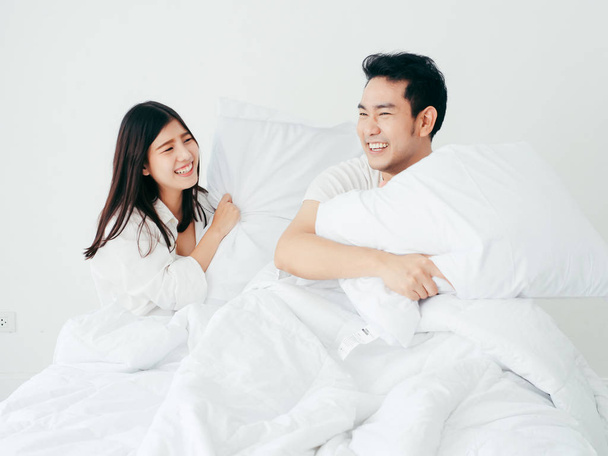 Happy Asian couple playing pillow on bed, lover lifestyle concep - Φωτογραφία, εικόνα