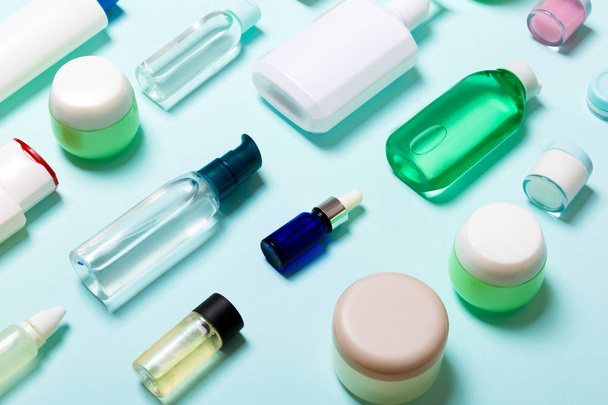 Top uitzicht van cosmetische producten in verschillende potten en flessen op blauwe achtergrond. Close-up van containers met Kopieer ruimte - Foto, afbeelding