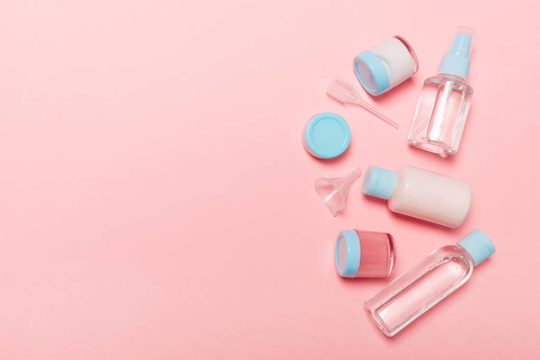 Top view composition of small travelling bottles and jars for cosmetic products on pink background. Facial skin care concept with copy space for your design - Foto, Imagen