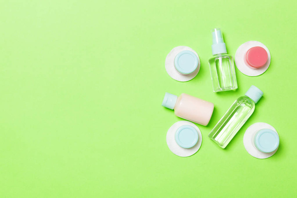Top view of means for face care: bottles and jars of tonic, micellar cleansing water, cream, cotton pads on green background. Bodycare concept with empty cpace for your ideas - Photo, Image