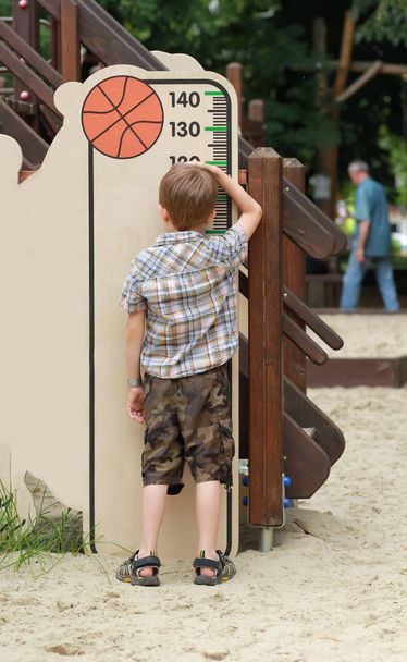 Beş yaşında bir çocuk çocuk oyun alanı üzerinde onun yükseklik ölçme - Fotoğraf, Görsel