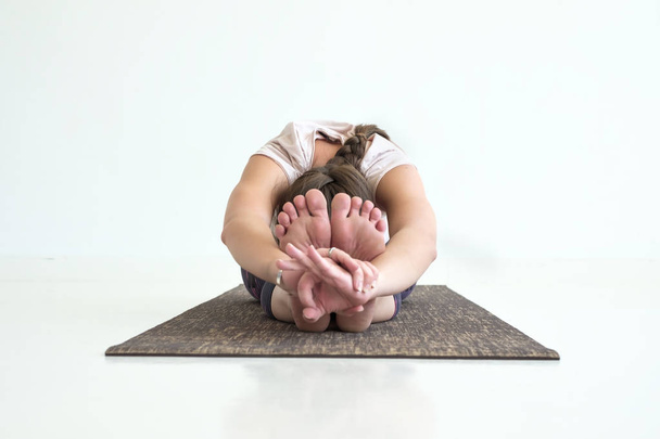chica practicando yoga, pose inclinada hacia adelante sentada, haciendo ejercicio paschimottanasana
 - Foto, imagen