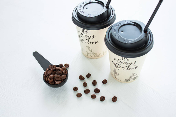 Papieren koffiekop van koffieshop met koffiebonen in de buurt van het raam. Lifestyle concept. - Foto, afbeelding