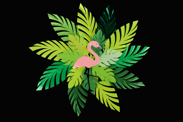 Top weergave van papier gesneden groene bladeren en roze flamingo geïsoleerd op zwart, achtergrond patroon - Foto, afbeelding