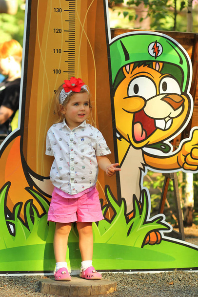  Mały maluch dziewczyna mierząc jej wysokość przed wejściem do parku linowego - Zdjęcie, obraz