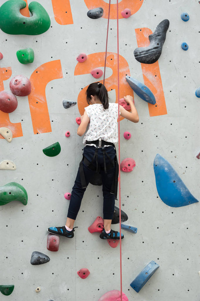 Vrouwelijke kind muur klimmer tijdens het klimmen van een hoge muur. Muurklimmen - Foto, afbeelding