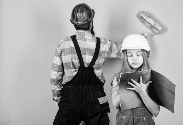 Family remodeling house. Little fathers helper. Father bearded man and daughter hard hat helmet uniform renovating home. Home improvement activity. Kid girl planning renovation. Child renovation room - Foto, Bild
