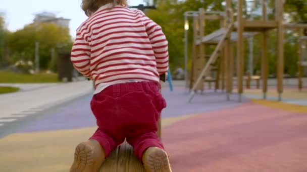 Mała dziewczynka gra na drewnianej huśtawce - Materiał filmowy, wideo