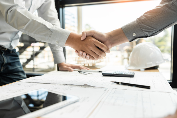 Architect and engineer construction workers shaking hands while working for teamwork and cooperation concept after finish an agreement in the office construction site, success collaboration concept  - Foto, immagini