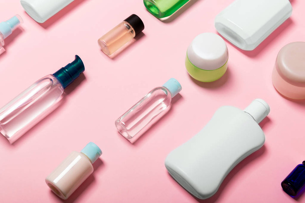Top zicht van cosmetische containers, sprays, potten en flessen op roze achtergrond. Close-up weergave met lege ruimte voor uw ontwerp - Foto, afbeelding