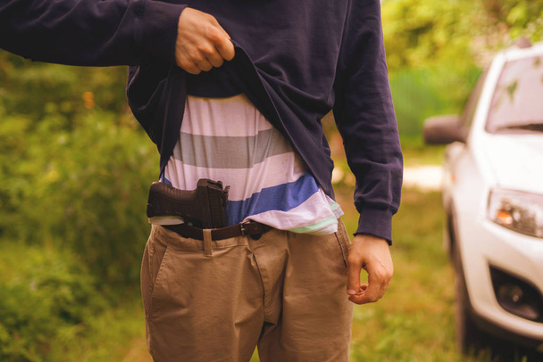 Грабитель в маске держит и перезаряжает пистолет на открытом воздухе
 - Фото, изображение