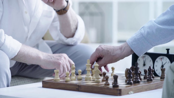 töprengő vezető férfi megérinti az asztalra, és figyeli az ellenfél mozog, miközben sakkozás a nappaliban - Felvétel, videó
