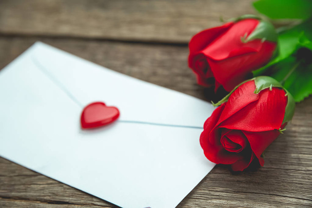 κόκκινο τριαντάφυλλο λουλούδια και γράμμα σε ξύλινο τραπέζι - Φωτογραφία, εικόνα
