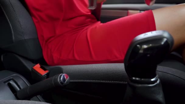 Kobieta w czerwonej sukni mocowania pasa bezpieczeństwa samochodowego siedząc wewnątrz pojazdu przed jazdą - Materiał filmowy, wideo