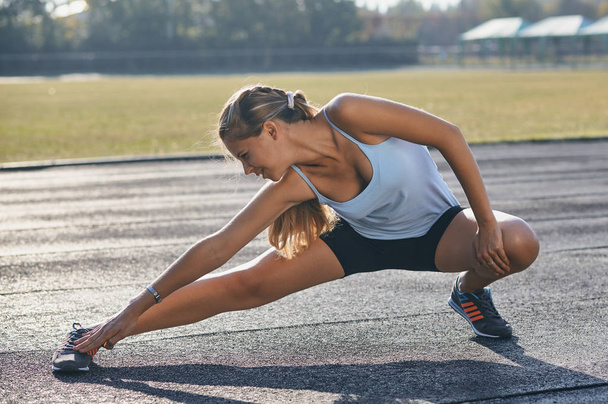 Young sportswoman stretching and preparing to run. - Foto, Imagen