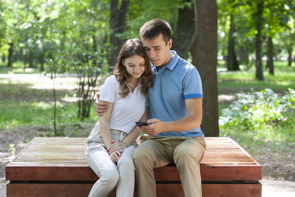 Parktaki bankta oturan genç ve güzel bir çift - Fotoğraf, Görsel