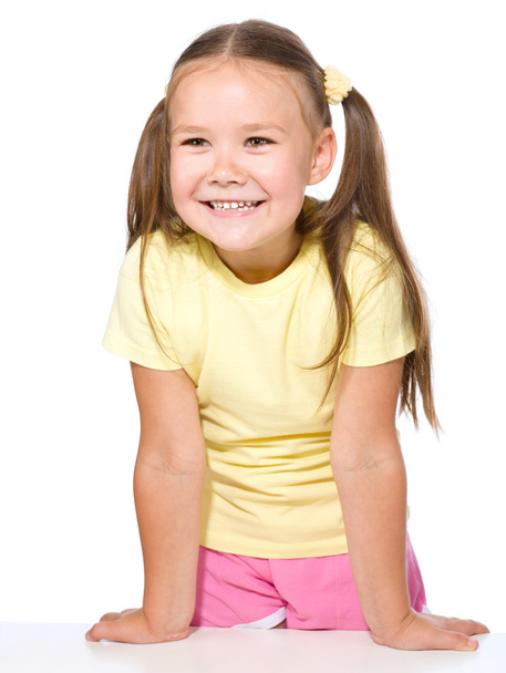 Portrait de heureuse petite fille appuyée sur une table
 - Photo, image