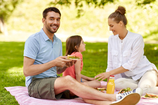 happy family having picnic at summer park - Фото, зображення
