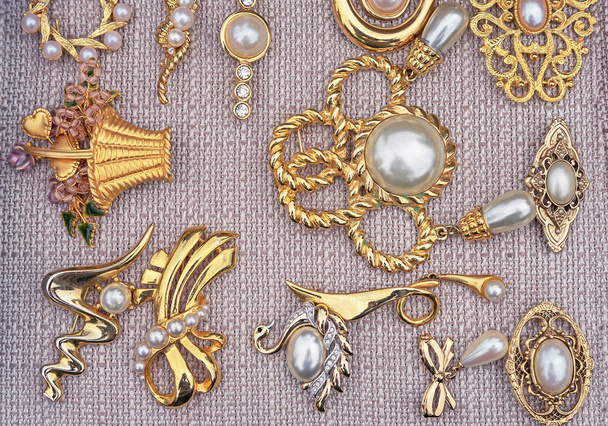 Brooches with pearls on a beige background. Jewelry background for design and decoration. - Photo, Image