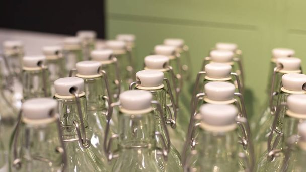 キャップと緑の背景を持つ再利用可能なガラスボトルの多く。廃棄物ゼロ、プラスチックコンセプトなし。環境と生態系のケア. - 写真・画像