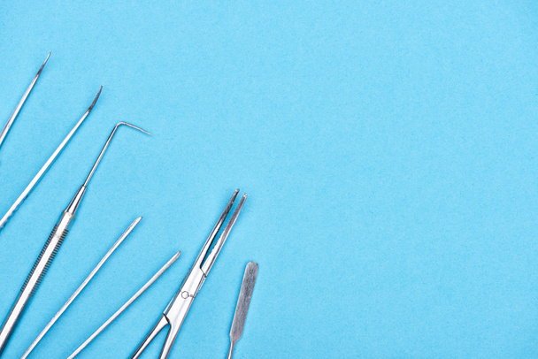 вид сверху с нержавеющими зубоврачебными инструментами, изолированными на голубом
  - Фото, изображение