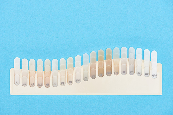 vista superior de amostras de dentes com diferentes tons isolados em azul
  - Foto, Imagem