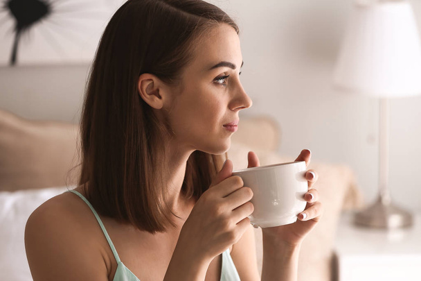 Beautiful young woman drinking tea at home - Foto, afbeelding